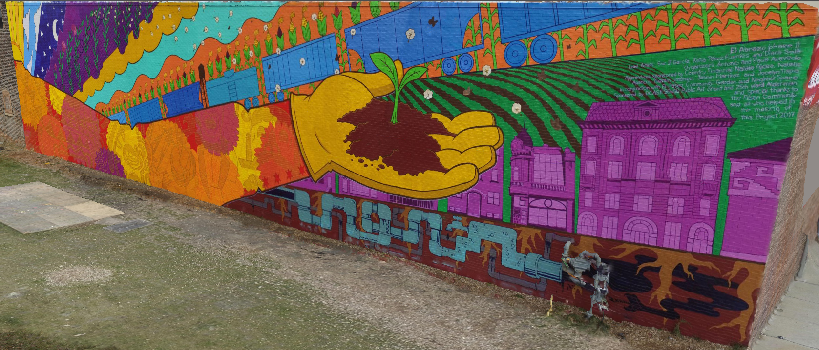 The gold arm of the mural “El Abrazo.” The palm of the hand is holding a plant sprouted in a pile of dirt. The mural depicts a railroad, reminiscent of the railroad once at the El Paseo garden site. There are also Pilsen homes above pipes underground. Additionally, scenes of day, night, and a field are shown. 